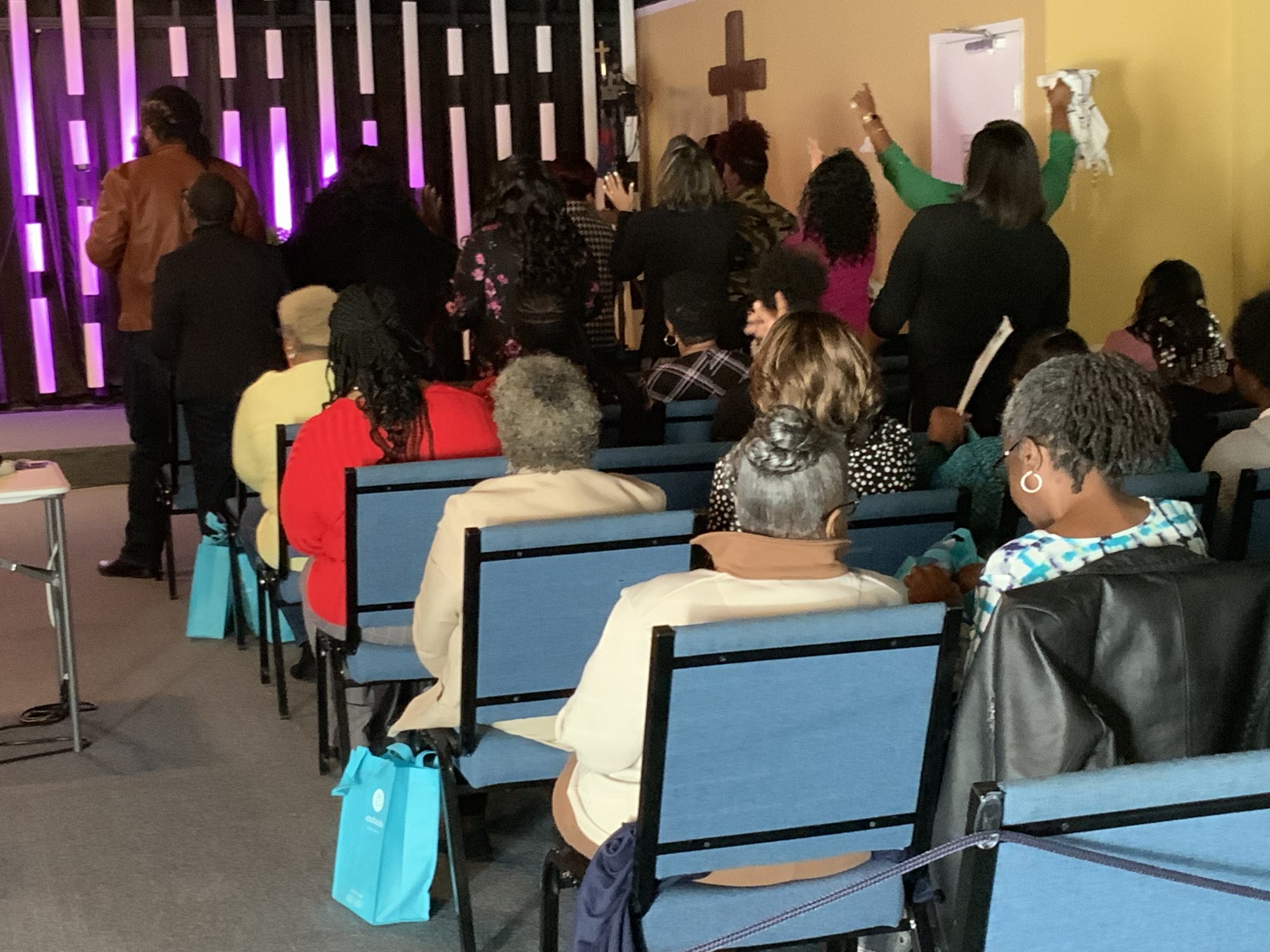 The Freedom congregation worshiping with hands raised toward the cross